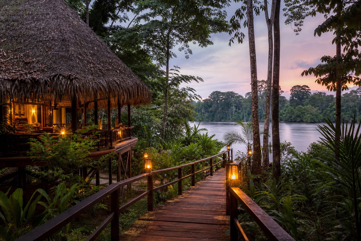 A thatched-roof Amazon eco-lodge at dusk